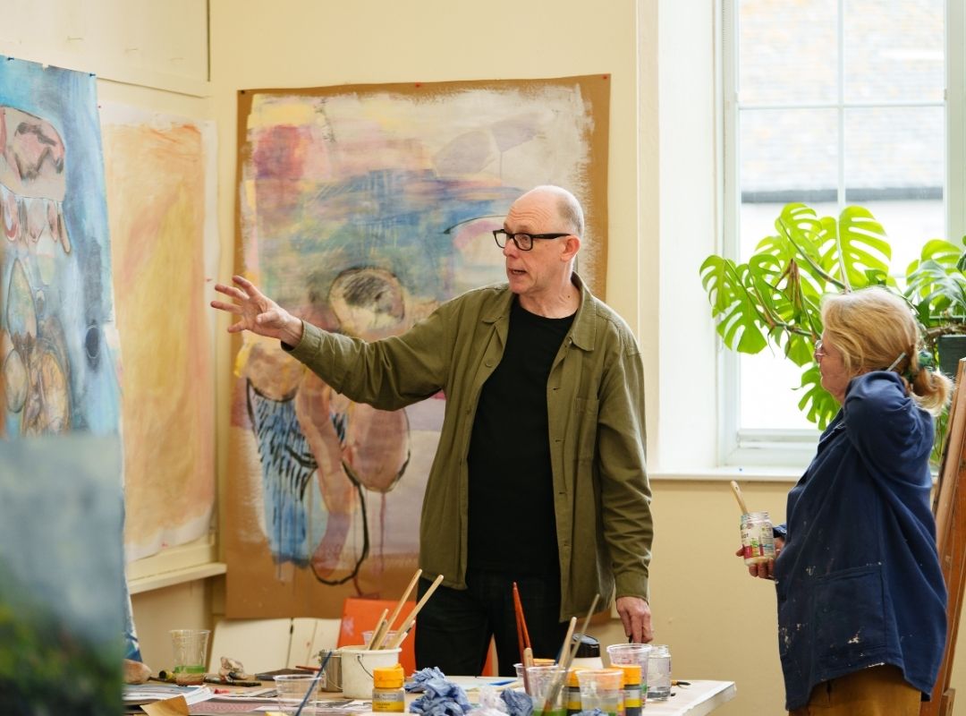 One to one support from Dan Pyne Artist Dan Pyne giving advice to an art student. Large canvases are pinned up on the walls around them.
